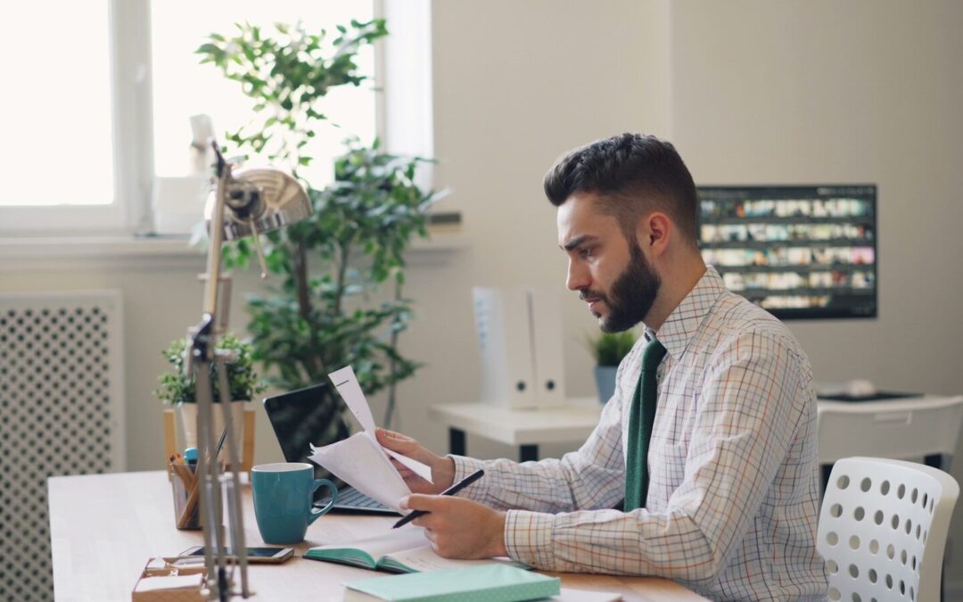a man sitting at a desk with a laptop and papers